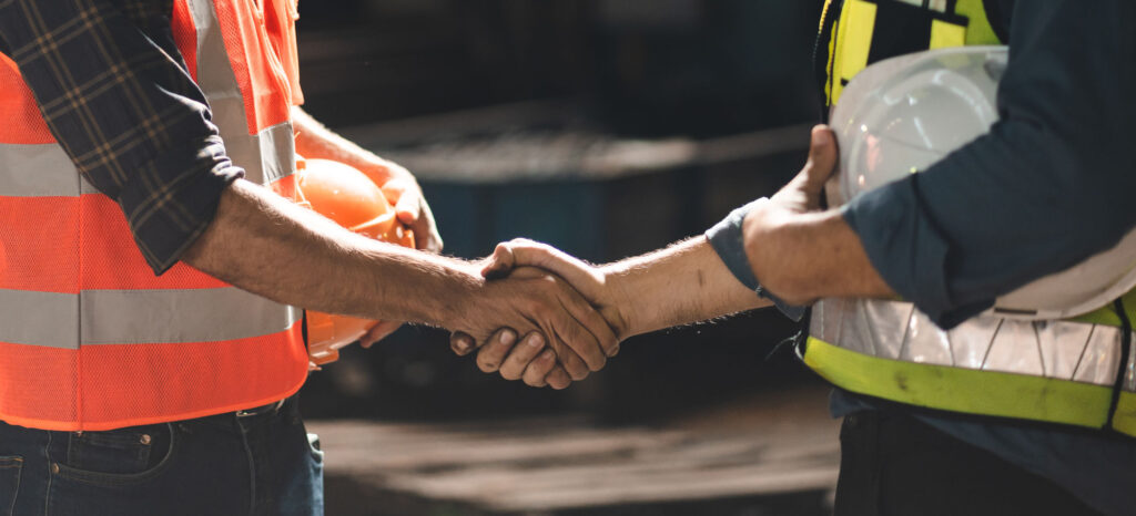 zdjęcie dwóch inżynierów ściskających swoje dłonie uzgadniających warunki naprawy maszyn